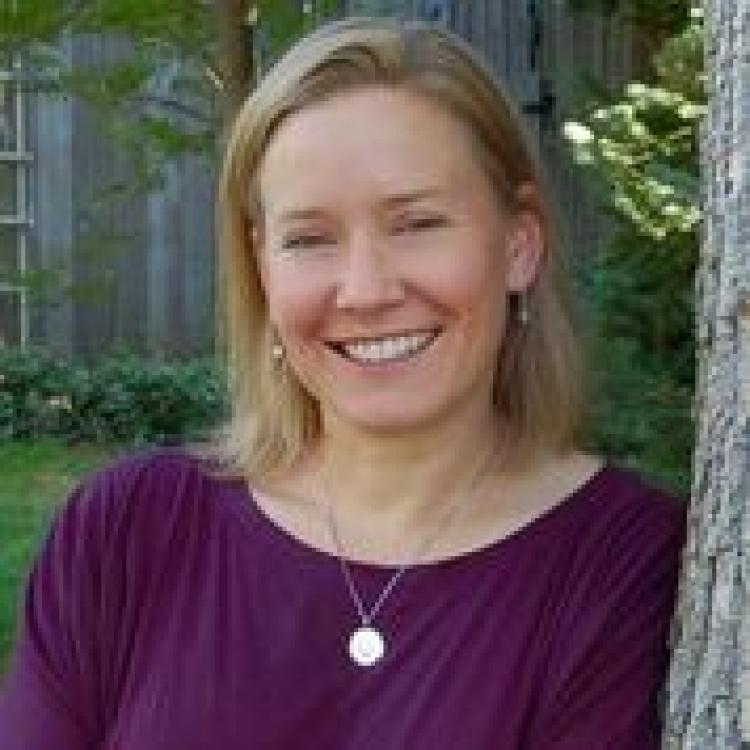 Portrait of a smiling Nancy Emery with trees in the background and to the left of her.