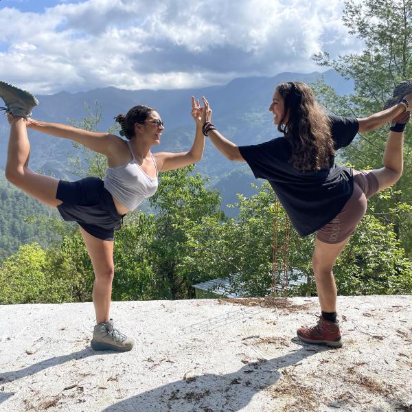 Two students doing yoga overlooking forest