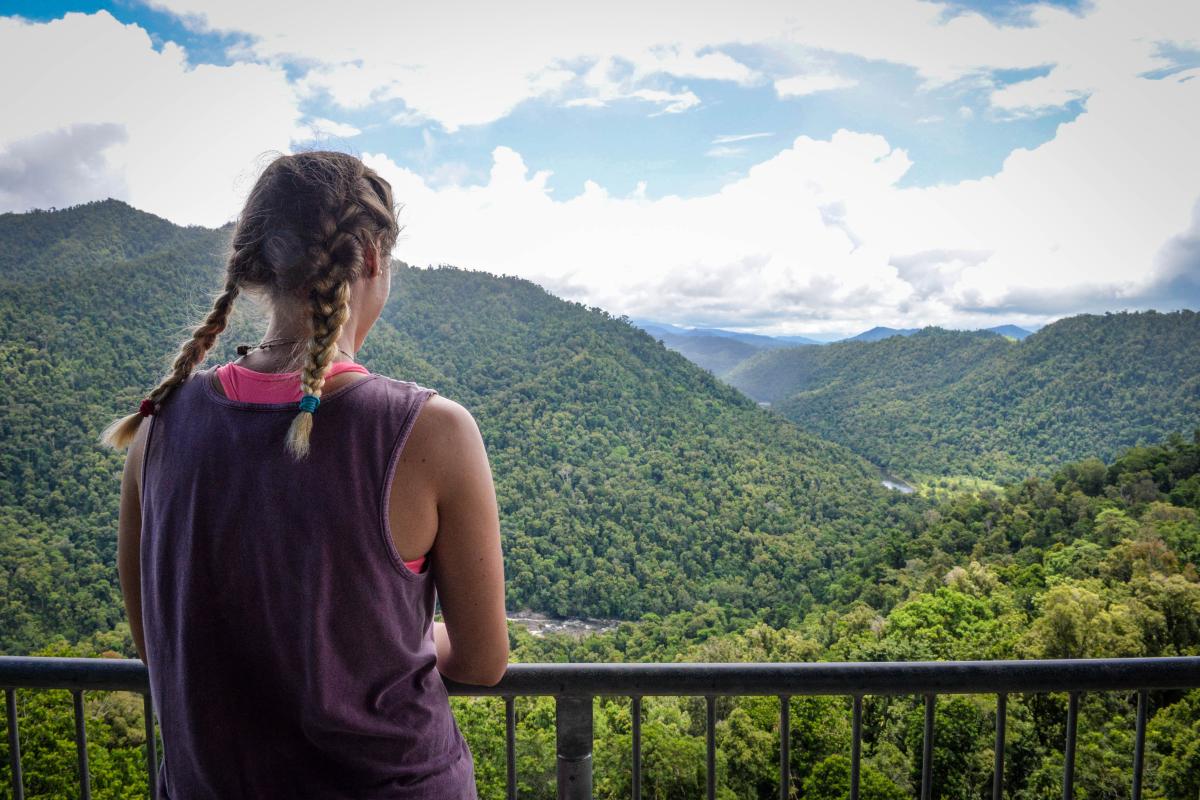 Student gazing at tree-covered mountains