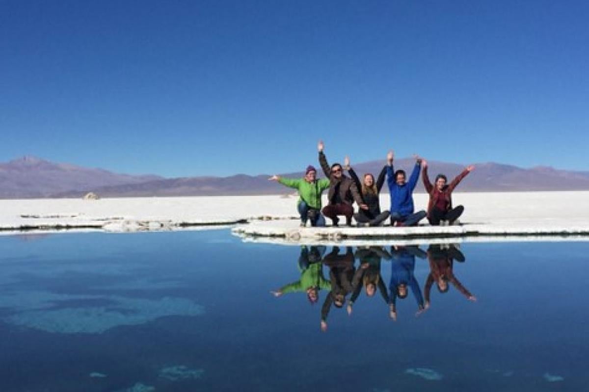 Students with hands raised by lake in Chile