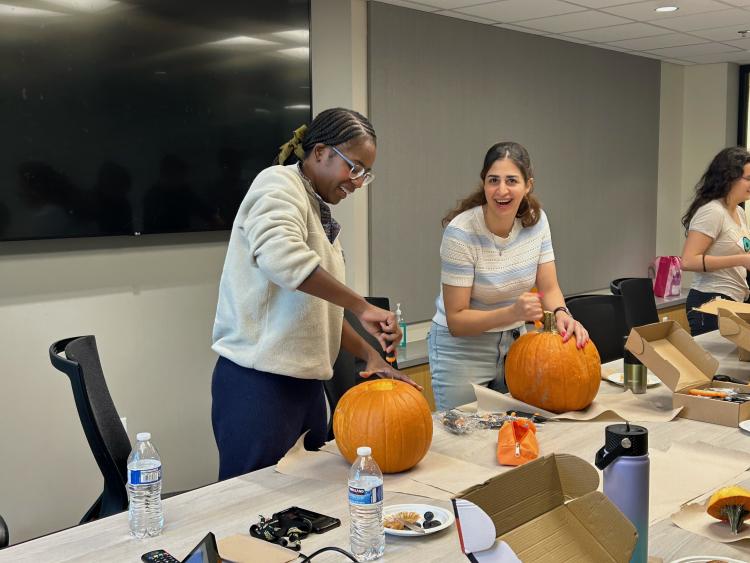 Norah Nyangau and Negar Rahimi carve pumpkins at the October Curci PhD Scholars monthly meeting.