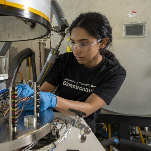 Amrita Singh working with a vacuum chamber.