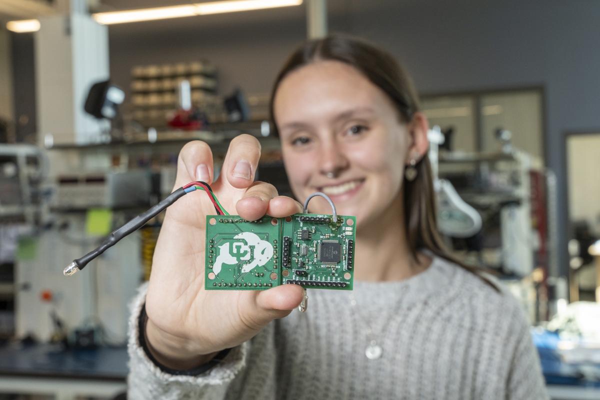 Student holding two printed circuit boards.