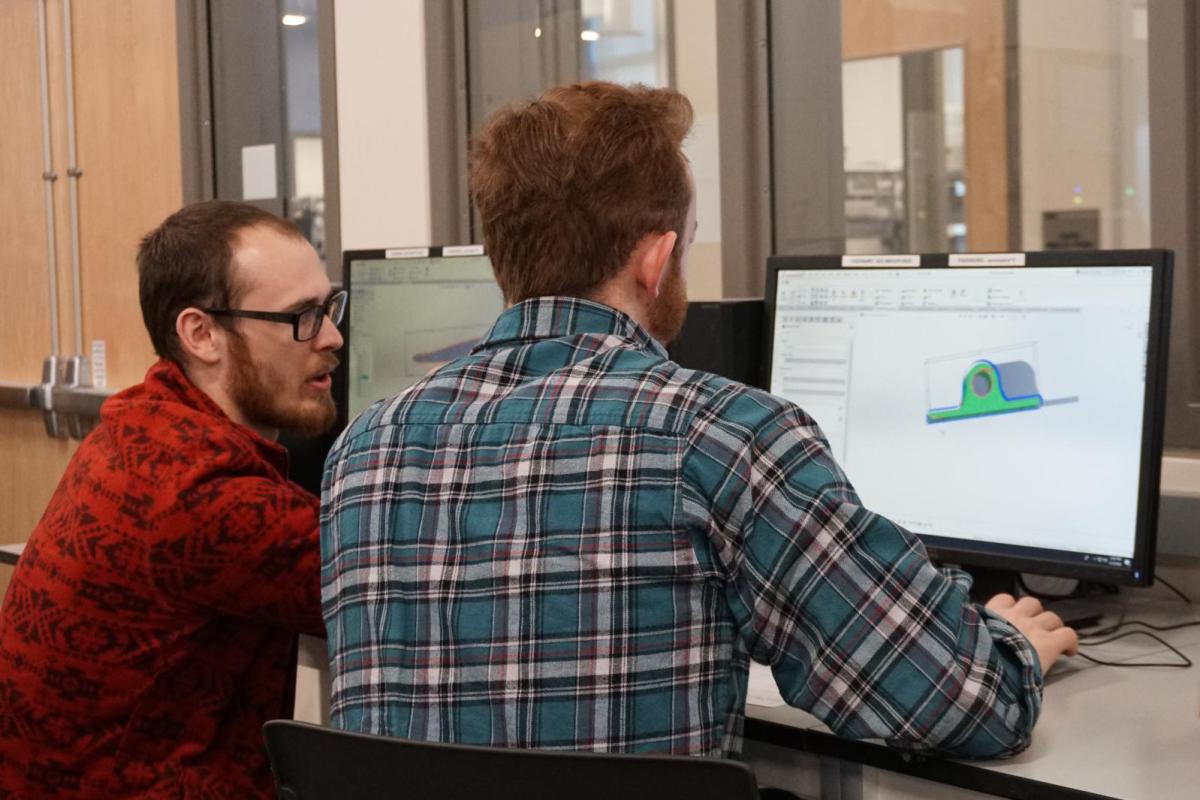 Nate Coyle working with a student in Solid Works.