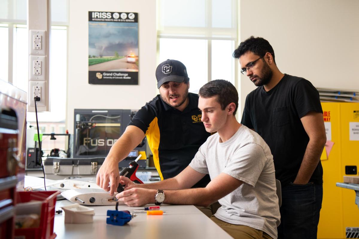 Two students working with a staff member on a UAV.