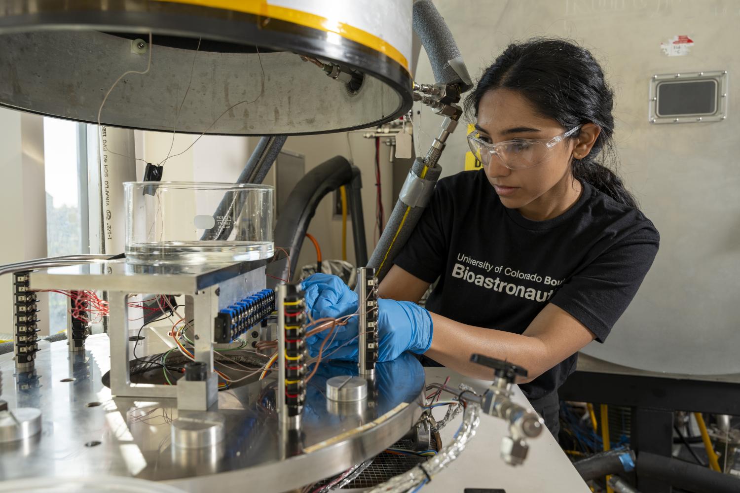 Amrita Singh working with a vacuum chamber.