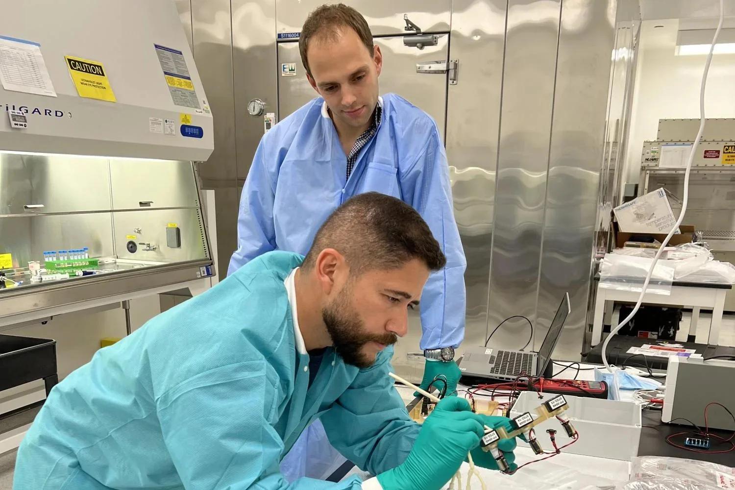 Zea and Niederwieser work on a component in the lab.