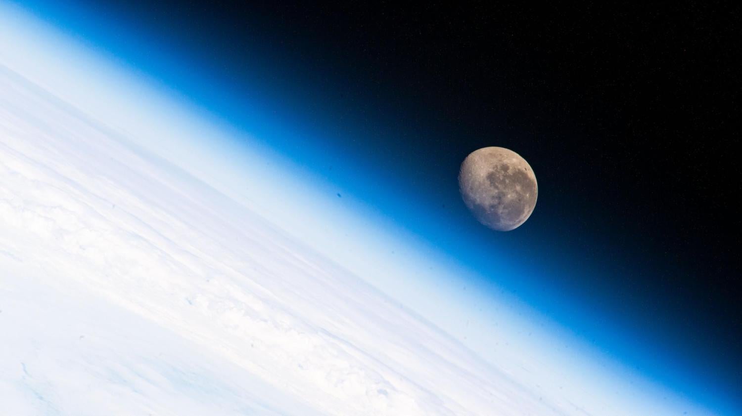 The waning gibbous Moon is pictured above the Earth's horizon as the International Space Station above the Atlantic Ocean.
