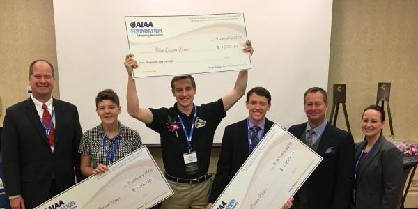 Students from the winning teams with oversized prize checks.