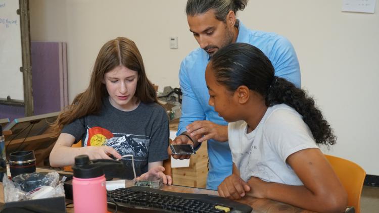 PhD graduate John Marino working with two high school students in the lab.