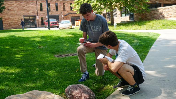 Two high school students testing their multispectral camera on objects in nature.