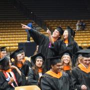 Students at graduation gesturing to the audience.
