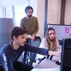 Three graduate students discuss a project in their office space