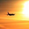 Plane flying toward a sunset.