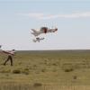 Two men launching fixed-wing UAVs.