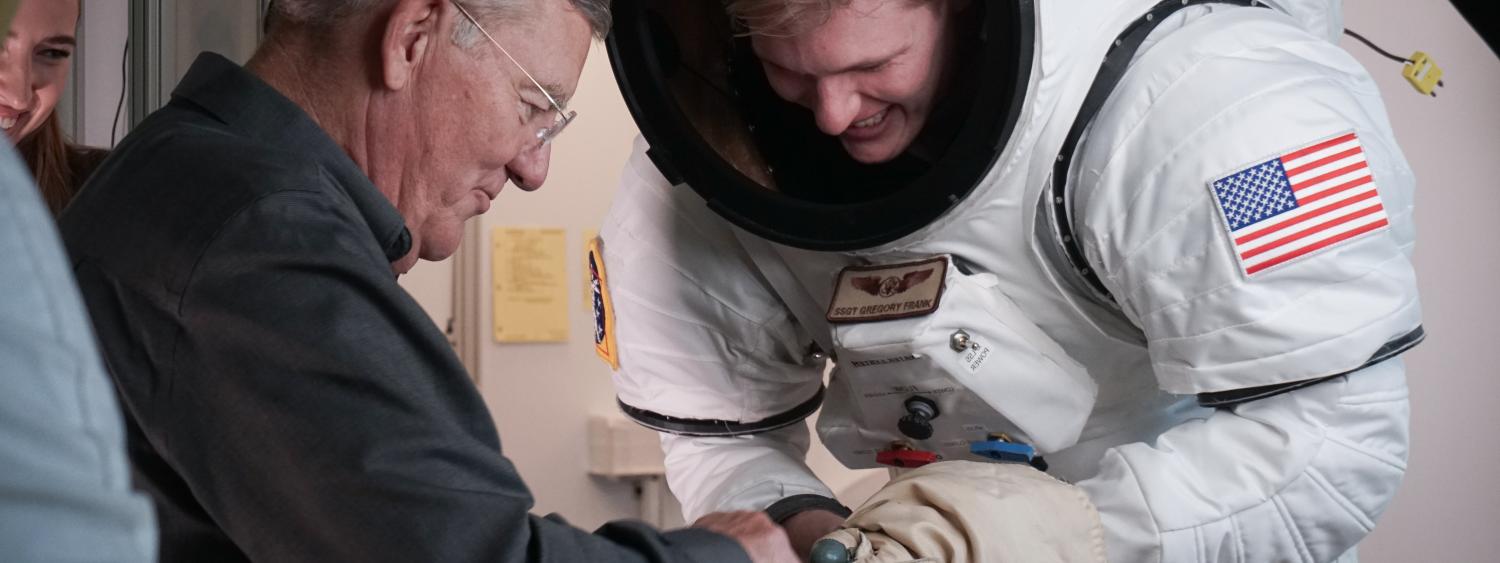 Voss helping a student gear up in a mock space suit.