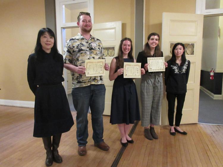 Three students standing and holding their certificates along with their instructors