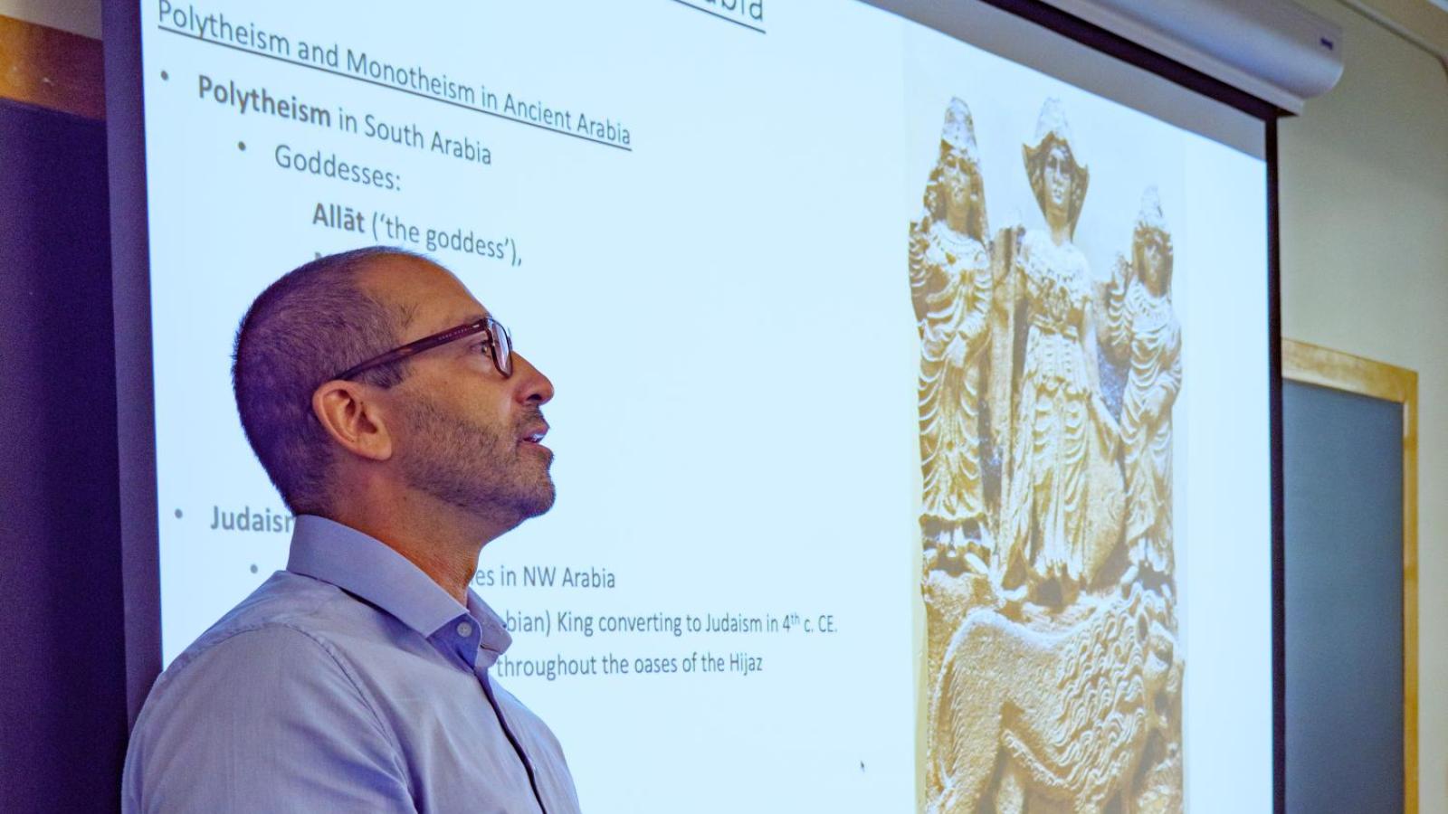 A male instructor standing in front of the presentation