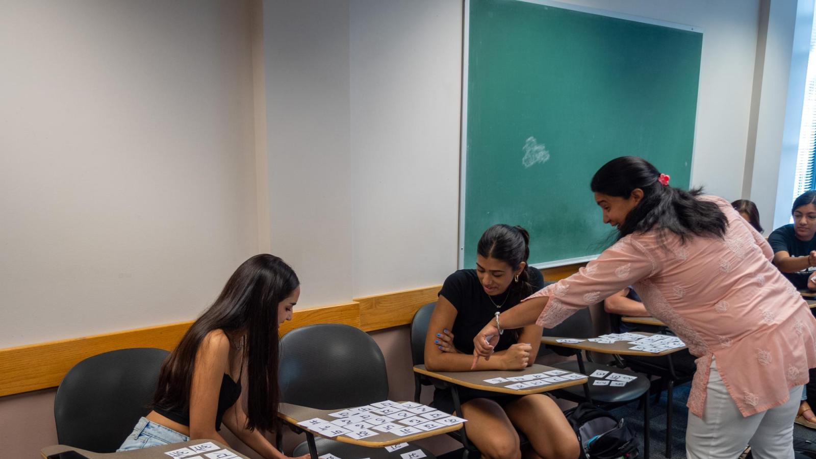 One female instructor teaching two female students Hindi alphabets