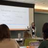 A female presenter is standing in front of the classroom