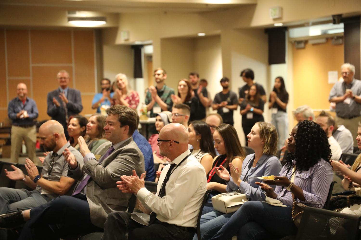 Crowd of people sitting and standing, clapping