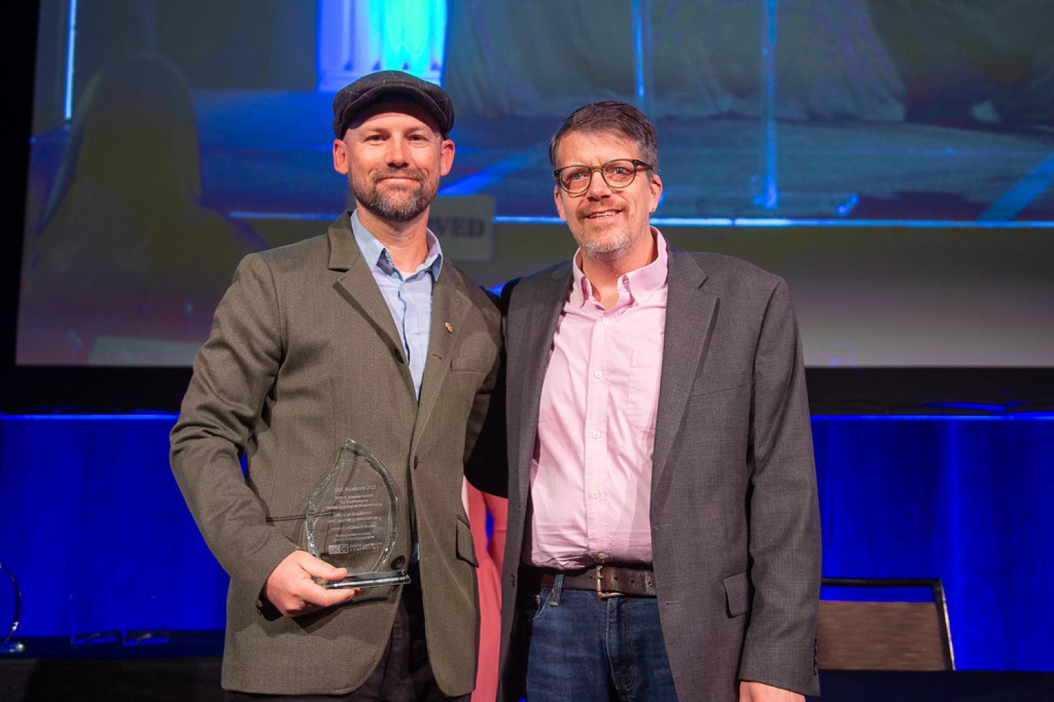 two people standing together with award
