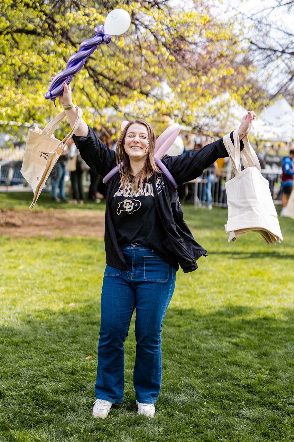 A CU Boulder grad celebrates her graduation on the lawn of the Alumni Association