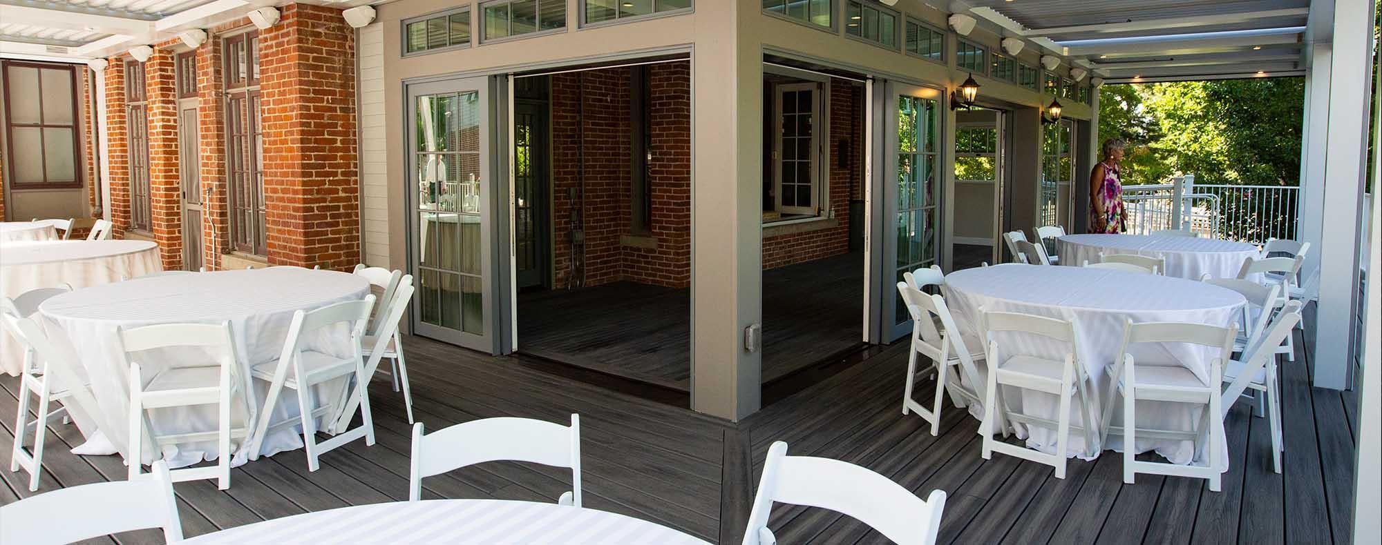 The covered outdoor patio of the Koenig Alumni Center, a historic house in Boulder, set up with event tables