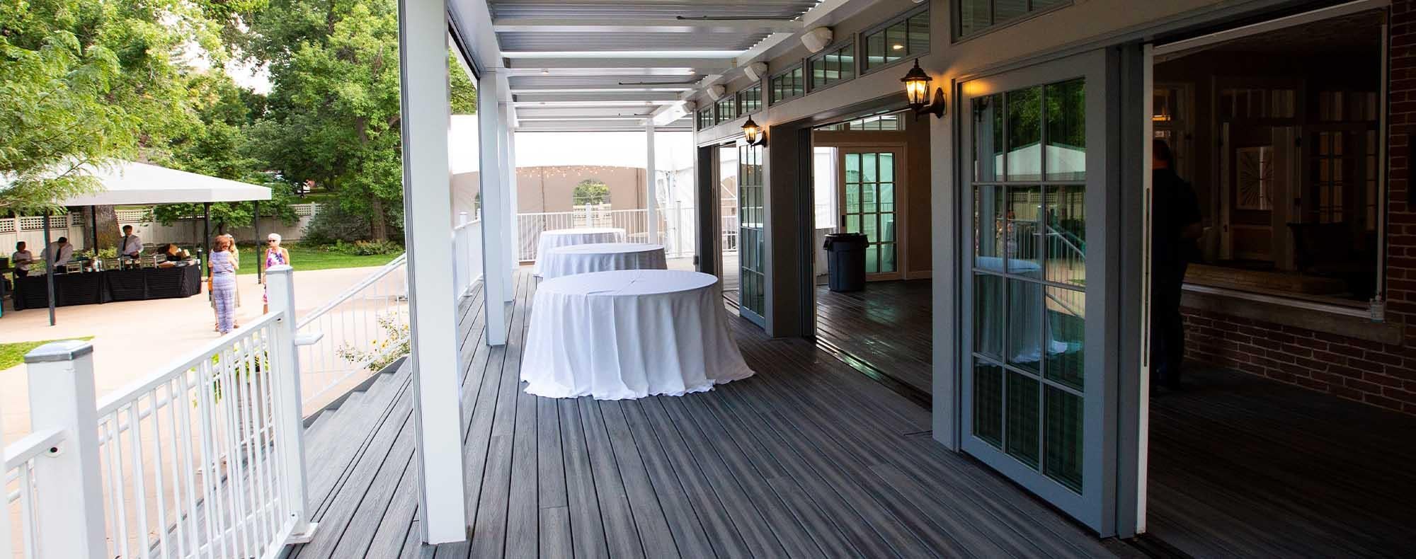 The covered outdoor patio of the Koenig Alumni Center in Boulder set up with event tables
