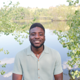 Olumide in front of a pond