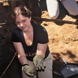  Dr. Hosek during the excavation and relocation of the Loretto Heights Cemetery in Denver (June 2022). She is holding one of the crosses affixed to the original coffins.
