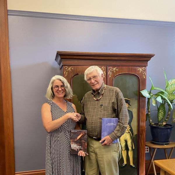 Carole and Warren shaking hands and holding books