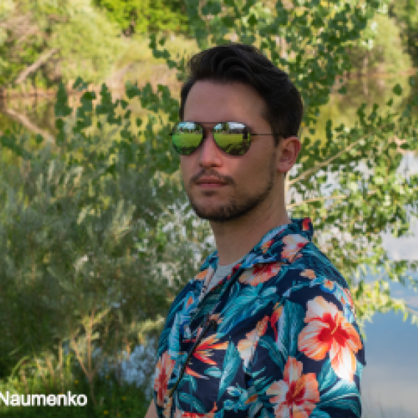 Daniel wearing sunglasses in front of a pond
