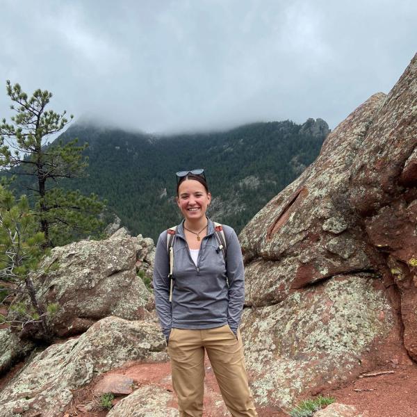 Kelsey on a hike standing in front of some rocks