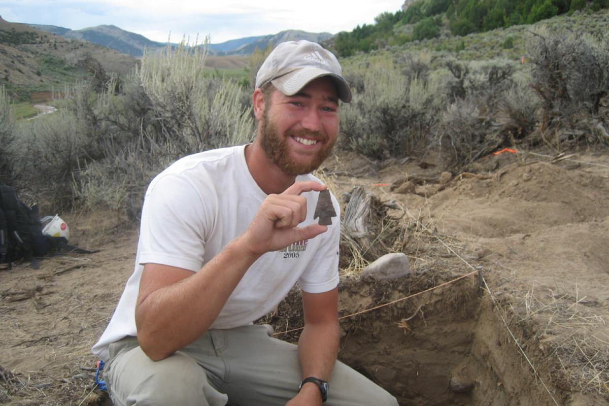 Lance Holly holding an arrow head in the field