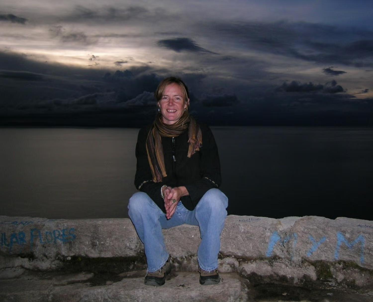 Carol Conzelman sitting on rocks in front of a lake