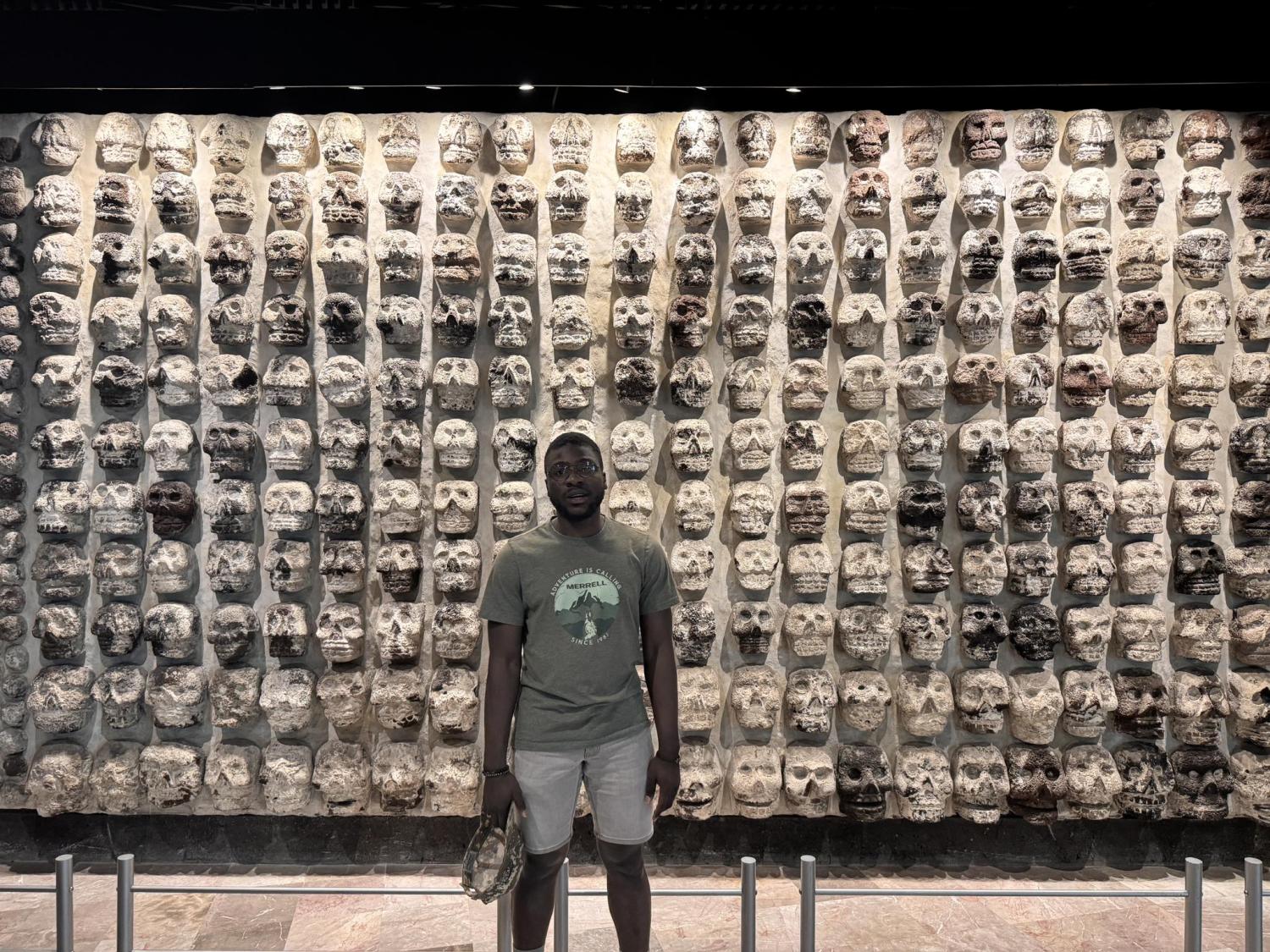 Olumide in front a wall of skulls