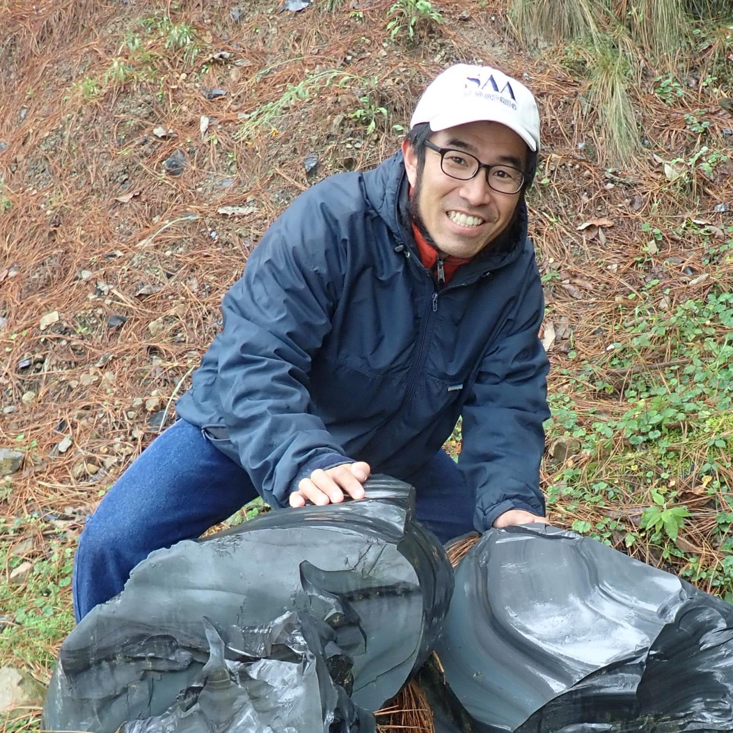 Akira Ichikawa in the field with big black rocks