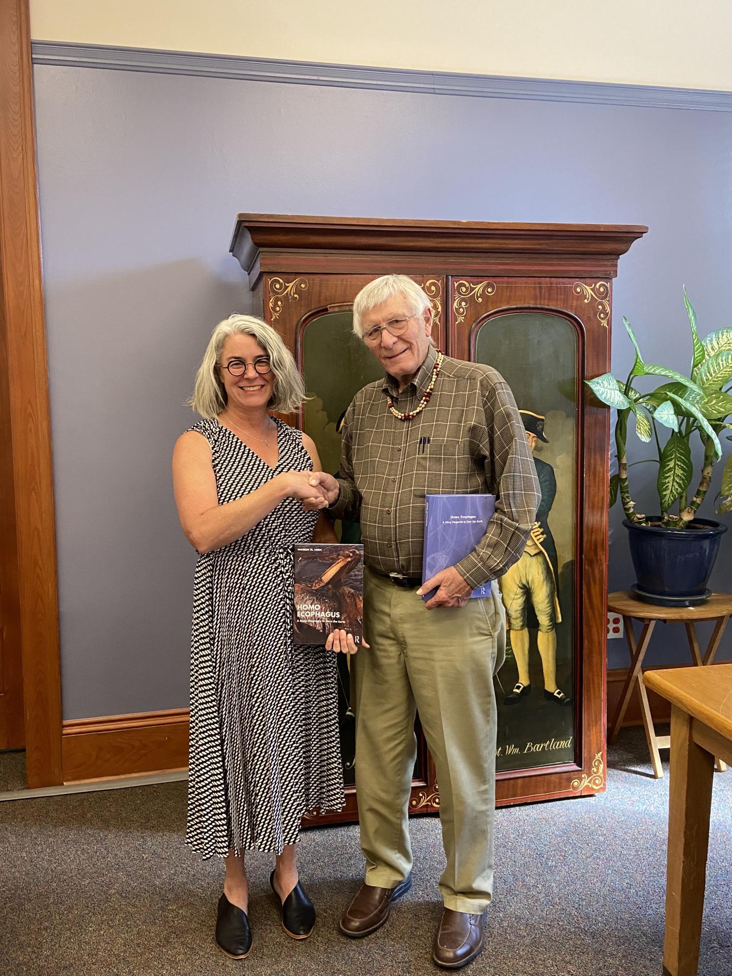 Carole and Warren shaking hands and holding books