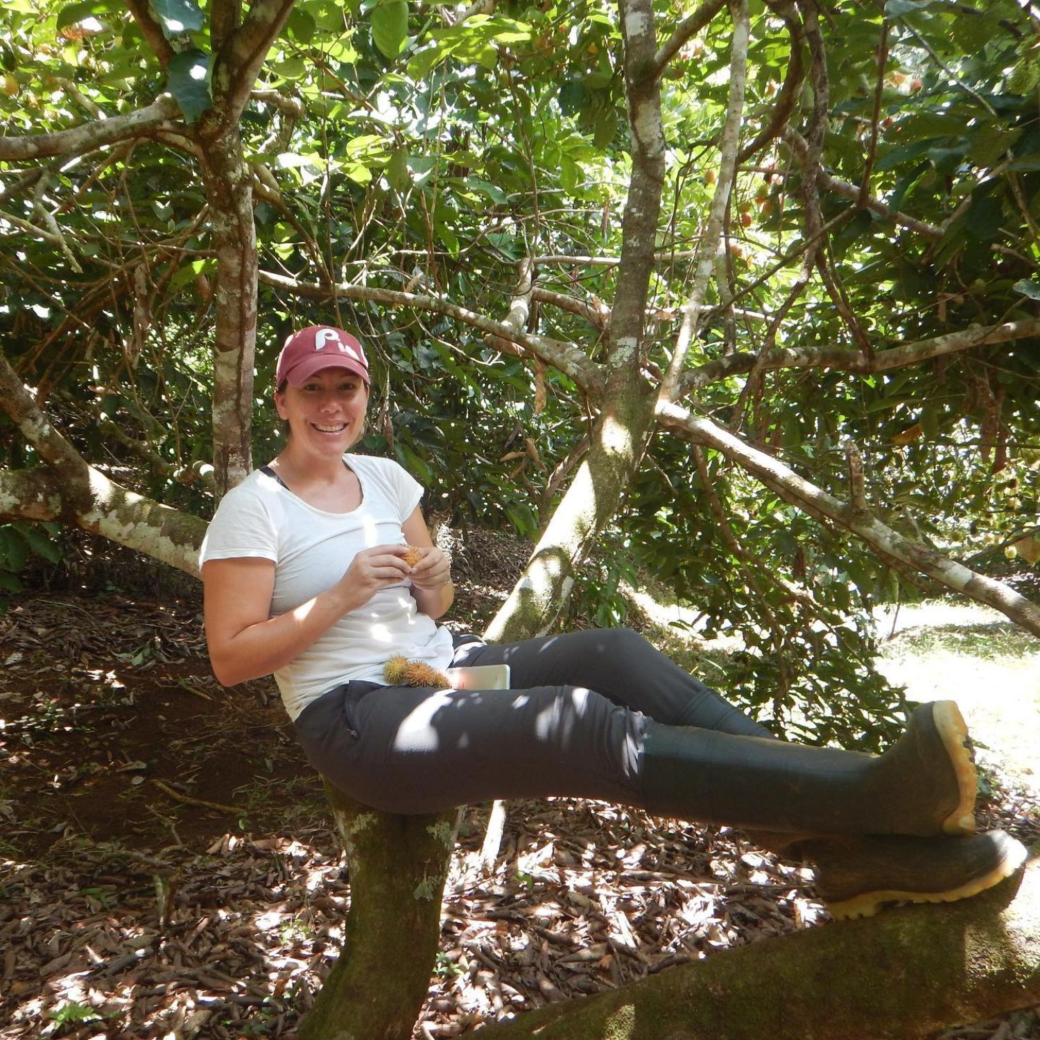 Emily Hite sitting in a tree eating a piece of fruit