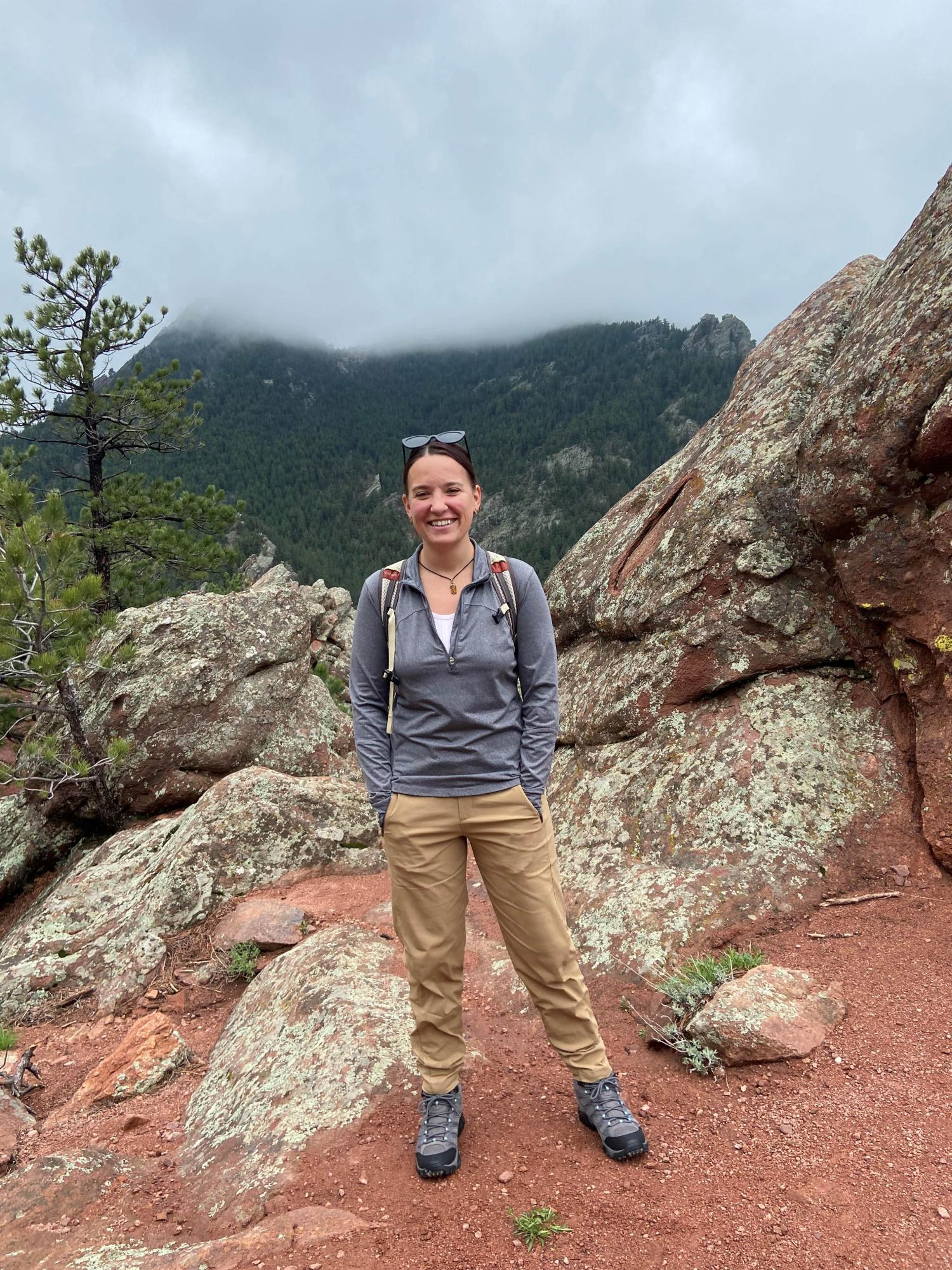 Kelsey on a hike standing in front of some rocks