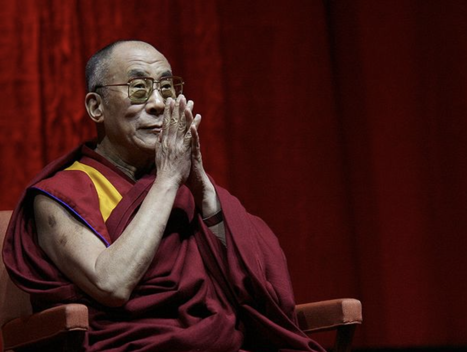 The Dalai Lama sitting with hands in prayer