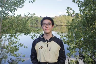 Yuxiang sitting in front of a pond