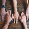 5 human hands on a wooden table
