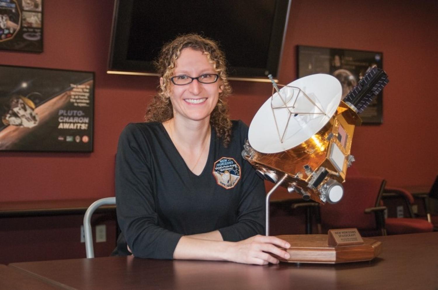 Kelsi Singer and a model of the New Horizons Spacecraft. Image credit: Rayna Tedford