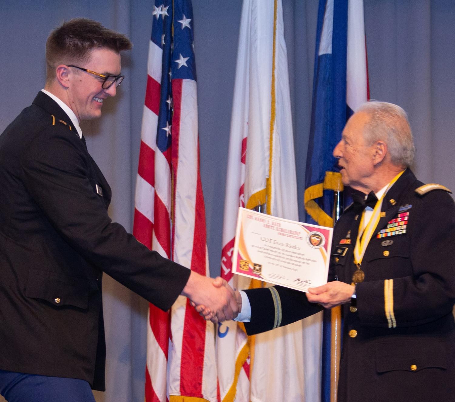 Cadet Evan Kistler shaking hands with COL (Ret.) Barry S. Baer as he receives the certificate for the 2022 Baer Scholarship. Photo courtesy of Tamara’s Camera, Erie, CO.