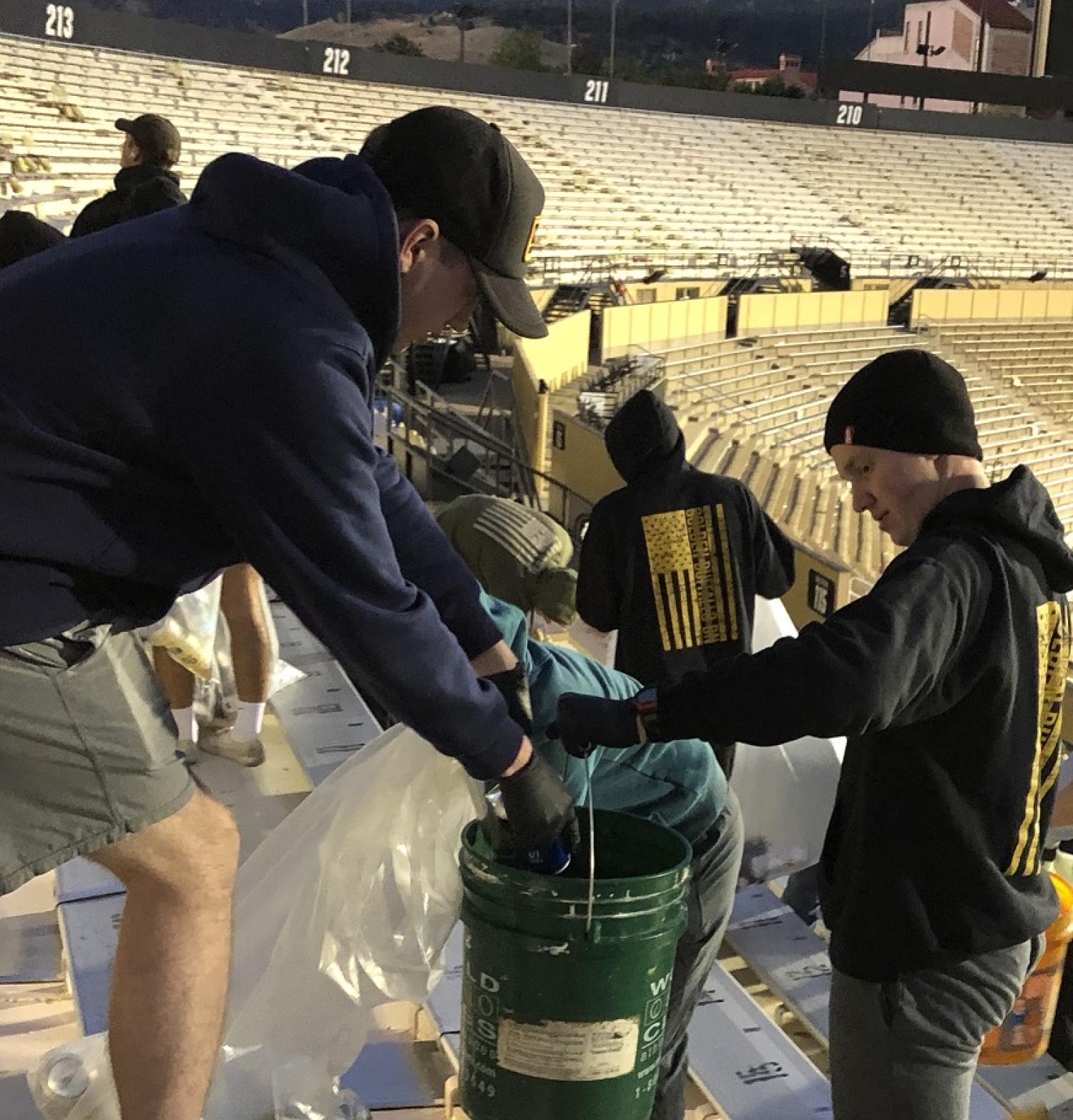 Army ROTC Cadet dumping out liquids into a bucket during the Stadium Clean-up on Sunday. Photo courtesy of the Golden Buffalo Battalion.