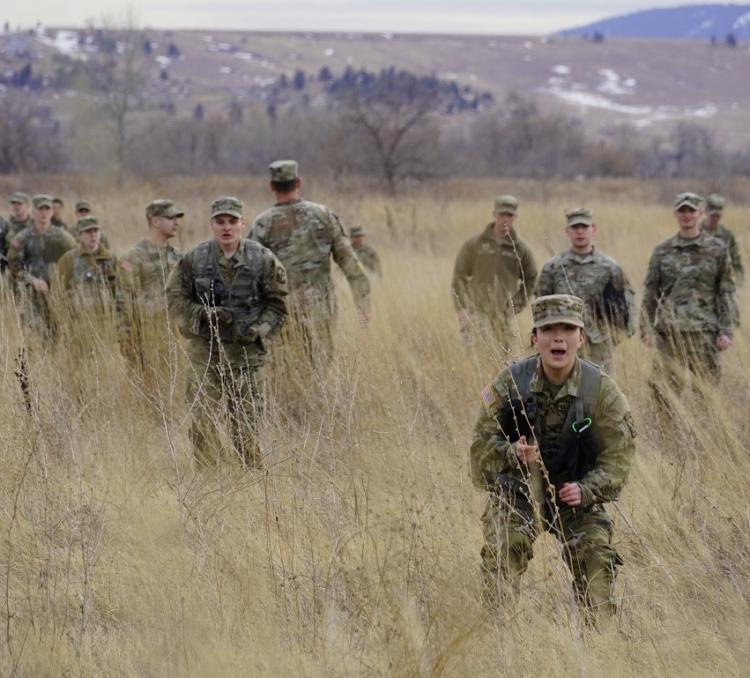 Platoon lead soldier yells a warning of enemy forces sighted and prepares to take cover, as the information is disseminated, the rest of the platoon ducks – as Cadre (middle with back turned) and MSIV Cadets (on the right) review and grade the entire process. Photo courtesy of CDT William Vlad.