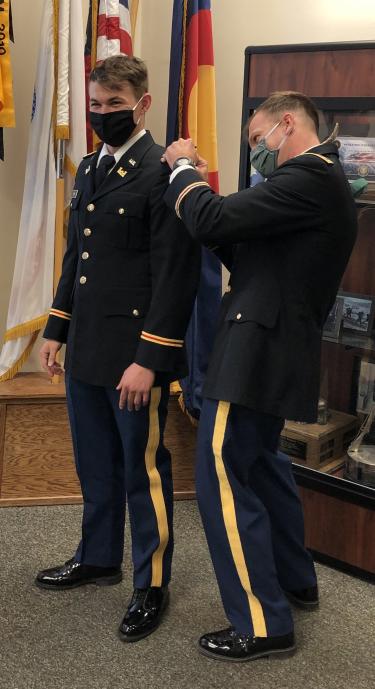 MAJ James is attaching the Second Lieutenant bars onto 2LT Goin’s officer uniform.