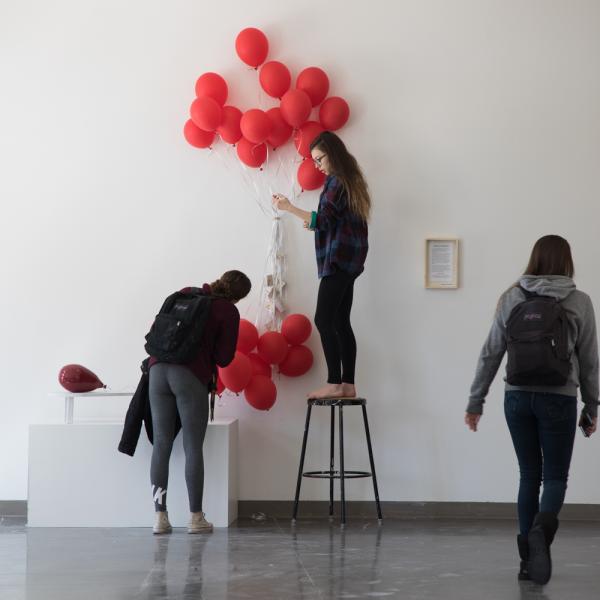 An undergraduate student setting up an installation to be exhibited on the first floor lobby in the VAC.